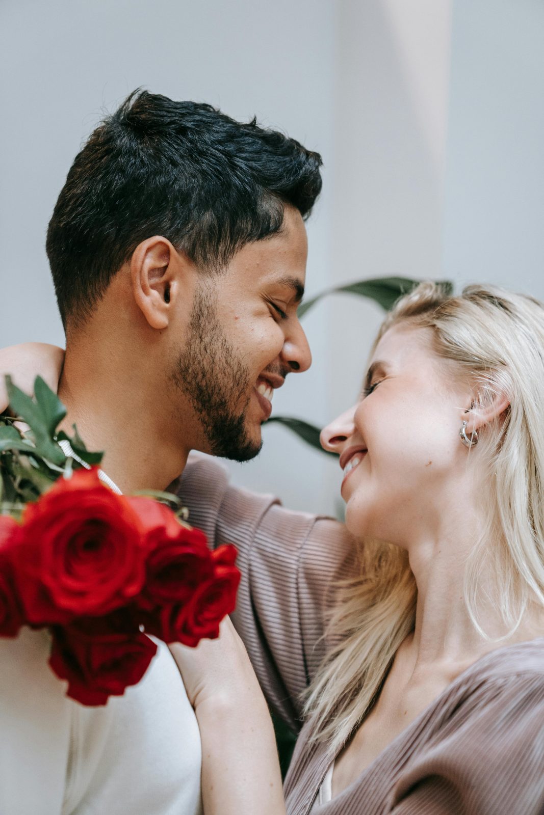 Casal apaixonado sorrindo com flores vermelhas - como arrumar um namorado